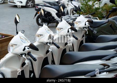 Motorcycles for rent or for sale on the city street. Lots of white scooters to ride. High quality photo Stock Photo