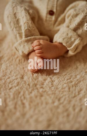 feet of a newborn, the baby is dressed in a warm knitted suit Stock Photo