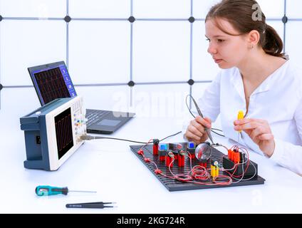 The concept of teaching electronic power supply circuit to students. Student studying the operation of an oscilloscope Stock Photo