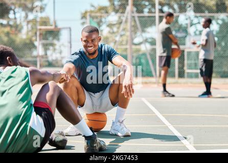 Sports, basketball and friends, men relax and fist bump on basketball court in happy summer. Friendship, teamwork and basketball player sitting on Stock Photo