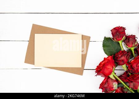 Envelope, blank paper and red roses bouquet, flat lay. Stock Photo