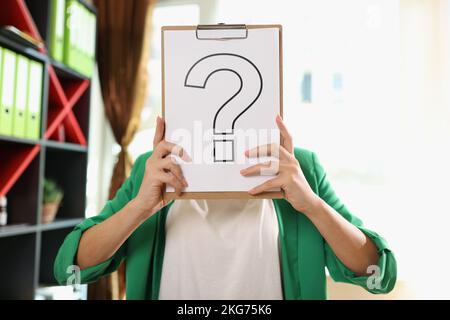 Confident business woman covering face with question mark sign Stock Photo