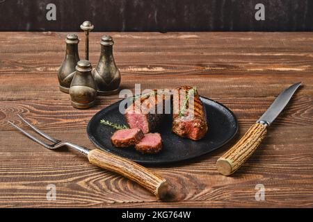 Roasted beef steak cut on slices on black plate Stock Photo