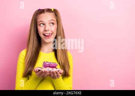 Photo of tricky cunning school girl dressed yellow top ready eating cake piece looking empty space isolated pink color background Stock Photo
