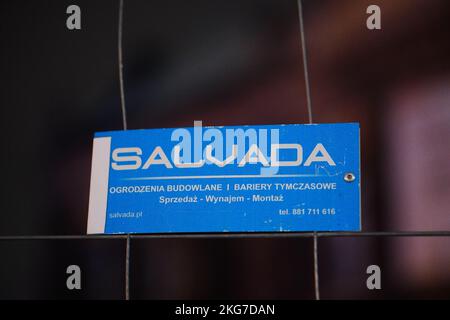 A blue Salvada company brand board on a construction fence in the night Stock Photo