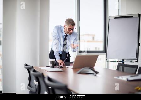 Handsome businessman having video call with his coworkers. Male professional shirt and tie while standing at office desk. Stock Photo