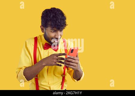 Young man gets message and looks at mobile phone with happy, surprised face expression Stock Photo
