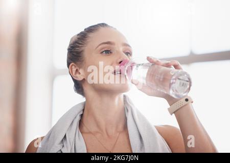 Water bottle, woman athlete and tired from indoor fitness workout, training exercise and thirsty or dehydrated after cardio. Body health wellness, h2o Stock Photo