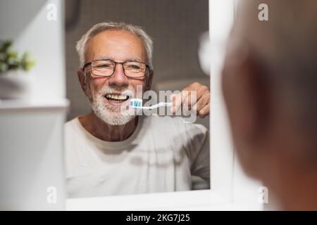 Senior man is cleaning his teeth in bathroom. Dental hygiene. Stock Photo