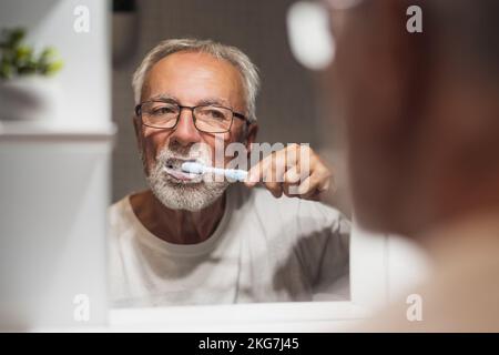 Senior man is cleaning his teeth in bathroom. Dental hygiene. Stock Photo