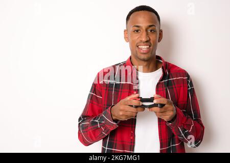 Man playing video game. Happy young man using joystick while playing video game isolated over white background. Stock Photo