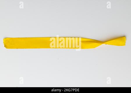 Ripped up piece of yellow tape with copy space on white background Stock Photo