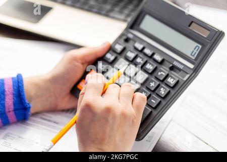Close up young woman using calculator, managing household monthly budget Stock Photo