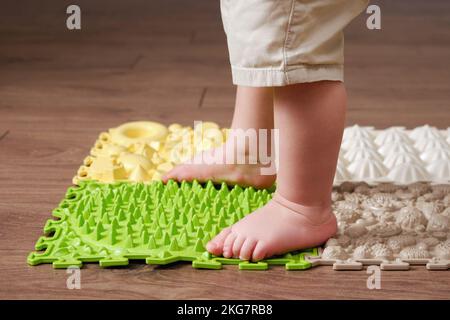 Baby toddler foots close-up on a medical orthopedic mat. Child legs with flat feet on a medical rug. Kid aged one year four months Stock Photo