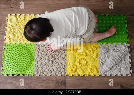 Baby toddler foots close-up on a medical orthopedic mat. Child legs with flat feet on a medical rug. Kid aged one year four months Stock Photo