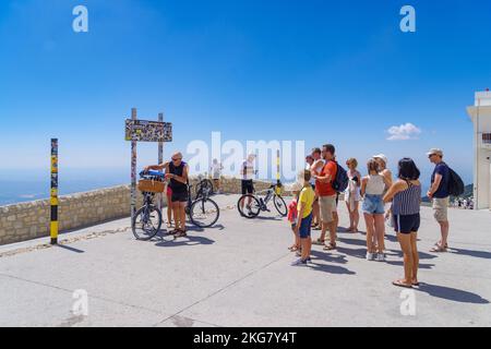 BEDOIN, FRANCE - AUGUST 7, 2022: Tourists on top of the Mont Ventoux waiting on their turn to take a picture under the nameplate. Stock Photo