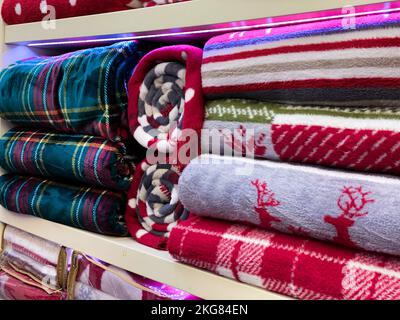 Bed linen, towels, sheets, blankets on storage shelves decorated for Christmas and New Years celebration. Stock Photo