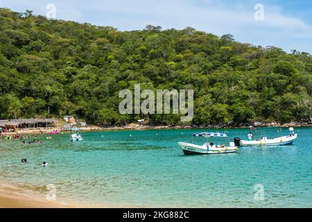 Tourists recreating on Maguey Beach in Huatulco National Park on the Pacific Coast of Oaxaca, Mexico.  A UNESCO Biosphere Reserve. Stock Photo