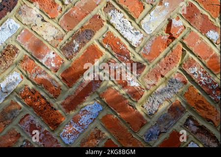 Red brick wall with herringbone design. This brick wall has an interesting pattern, varied colors and a rough texture. Brick wall in Beckenham, UK Stock Photo