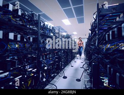 Female technician walking in server room Stock Photo