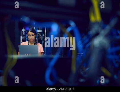Female technician using laptop in server room Stock Photo