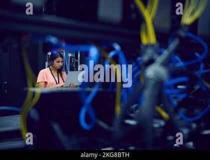 Female technician using laptop in server room Stock Photo