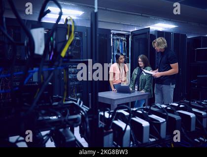 Team of technicians working in server room Stock Photo
