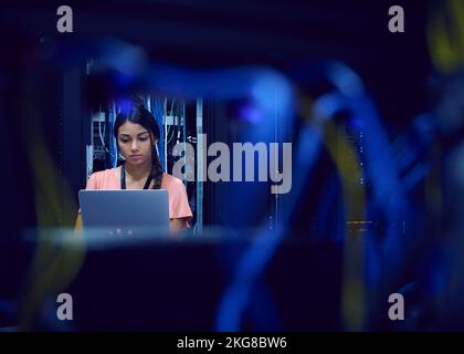 Female technician using laptop in server room Stock Photo