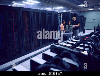 Team of technicians working in server room Stock Photo