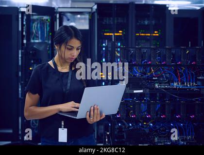 Female technician using laptop in server room Stock Photo