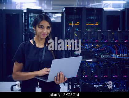 Portrait of smiling female technician using laptop in server room Stock Photo