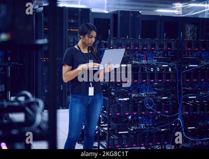 Female technician using laptop in server room Stock Photo