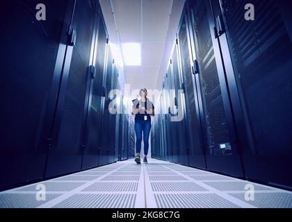 Female technician walking in server room Stock Photo