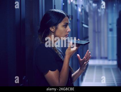 Female technician using smart phone in server room Stock Photo