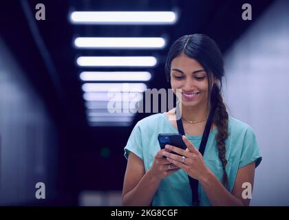 Smiling female technician looking at smart phone in data center Stock Photo