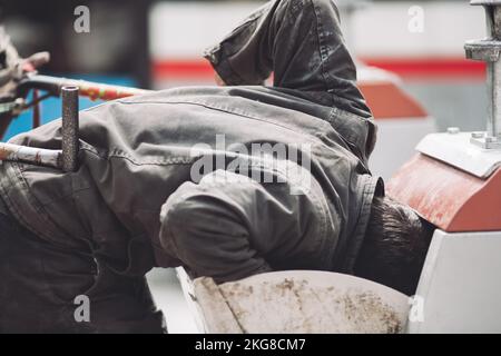 a homeless man is looking for food in a garbage can Stock Photo