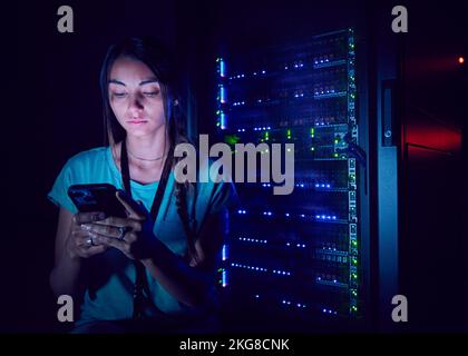 Technician using smart phone in server room Stock Photo