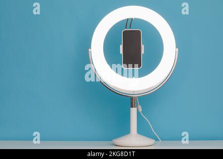 Ring light and smart phone on blue background Stock Photo