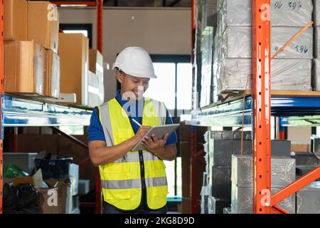 Asian warehouse worker checking the delivery status of the package with a tablet Stock Photo
