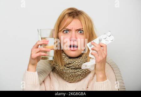 Woman wear warm scarf because illness or flu. Girl hold glass water tablets and thermometer light background close up. Getting fast relief. Ways to Stock Photo