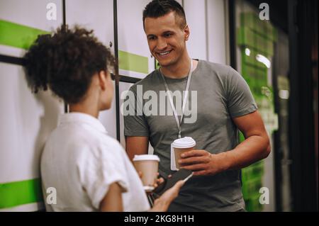 Joyful office worker talking to his female colleague during the coffee break Stock Photo