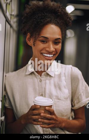Joyous employee with a disposable coffee paper cup posing for the camera Stock Photo