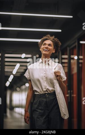 Joyful employee standing in the corridor and looking up Stock Photo