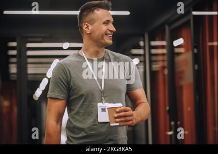 Smiling employee holding a beverage in a disposable paper cup Stock Photo