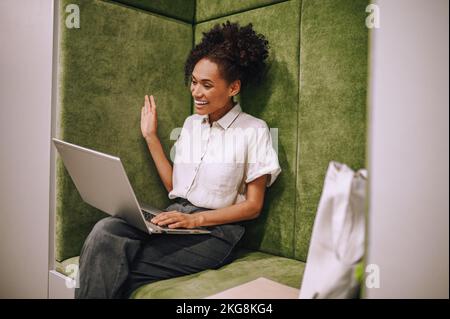 High-spirited beautiful young woman greeting somebody over Skype Stock Photo