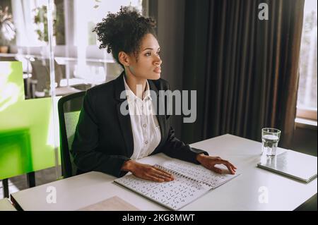 Visually impaired office worker seated at the table using Braille Stock Photo