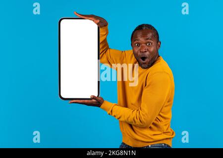 Amazed black man holding phone in both hands, mockup Stock Photo