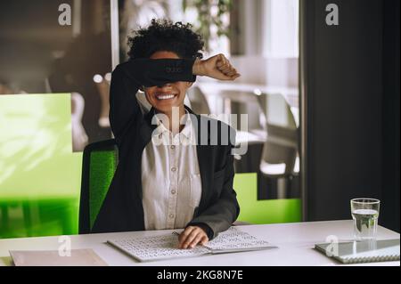 Visually impaired woman seated at the office table using Braille Stock Photo