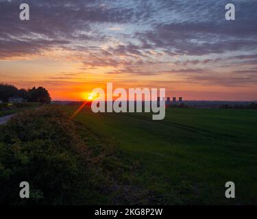 A Vibrant red sky over the fields of south Derbyshire looking towards the old disused wellington coal fired power station with cooling towers Stock Photo