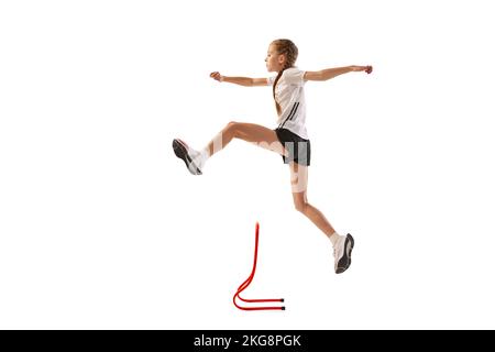 Dynamic portrait of little girl, professional athlete, runner, jogger at steeplechase training isolated over white background Stock Photo